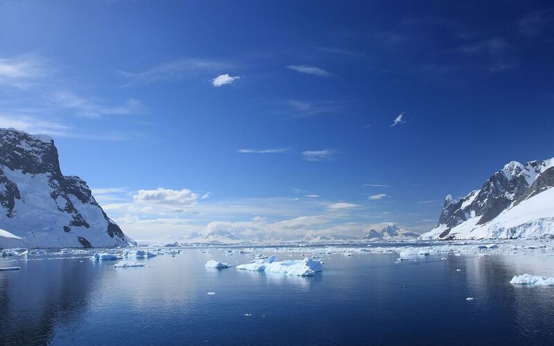 Kalme zee met drijfijs tussen besneeuwde bergwanden in het Lemaire Channel op het Antarctisch Schiereiland