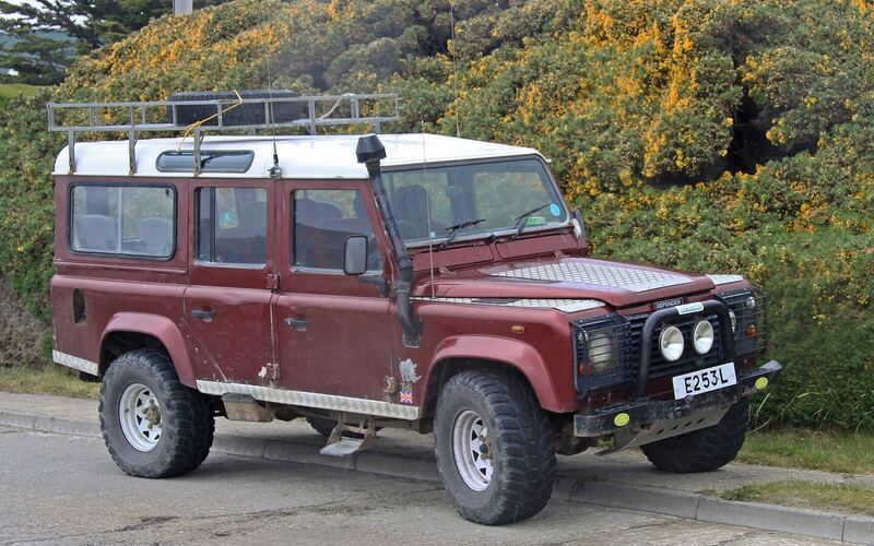 Rode Land Rover Defender geparkeerd langs een weg in Stanley op de Falklandeilanden