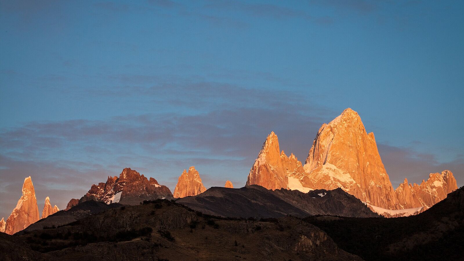 De pieken van de Fitz Roy kleuren oranje in het eerste ochtendlicht boven El Chaltén