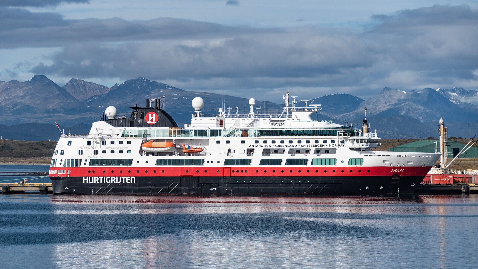Wit-rood expeditieschip aan de kade van Ushuaia met bergen op de achtergrond