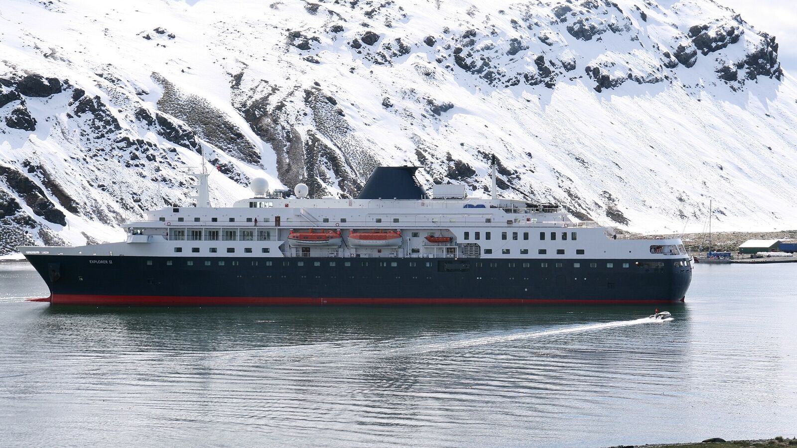 Expeditieschip voor anker in de baai bij Grytviken op Zuid-Georgië, met besneeuwde bergen erachter