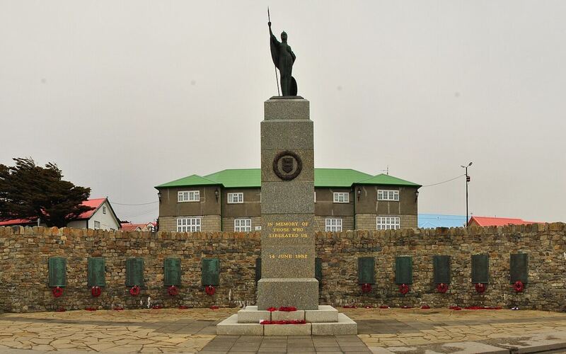 Het 1982 Liberation Memorial in Stanley met een bronzen Britannia op een zuil voor een gebogen muur met gedenkplaten