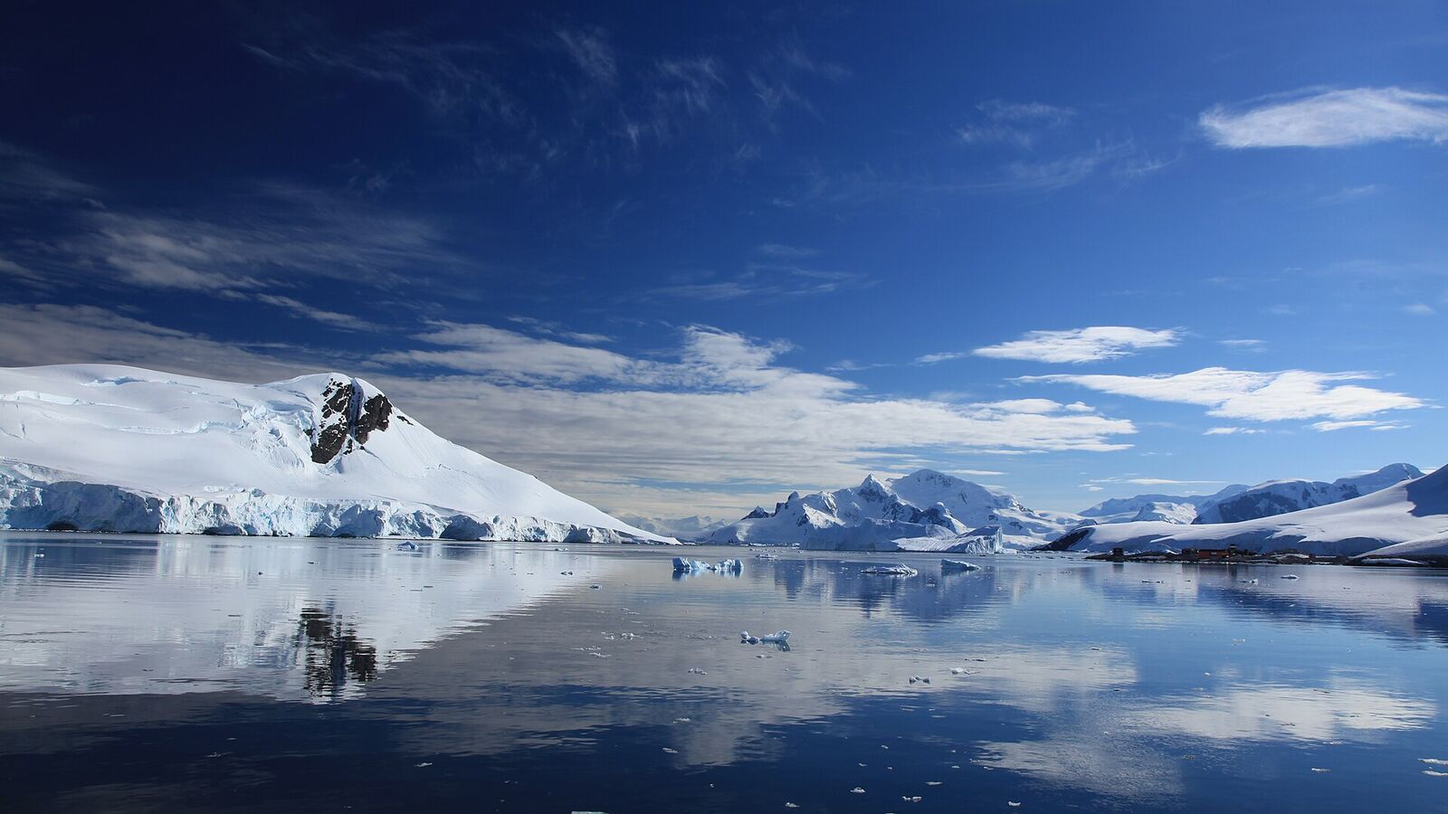 Besneeuwde bergen en gletsjers weerspiegelen in het kalme water van Paradise Harbour in Antarctica