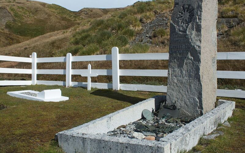 Het graf van Ernest Shackleton met granieten grafsteen achter een wit hek op de walvisvaardersbegraafplaats van Grytviken