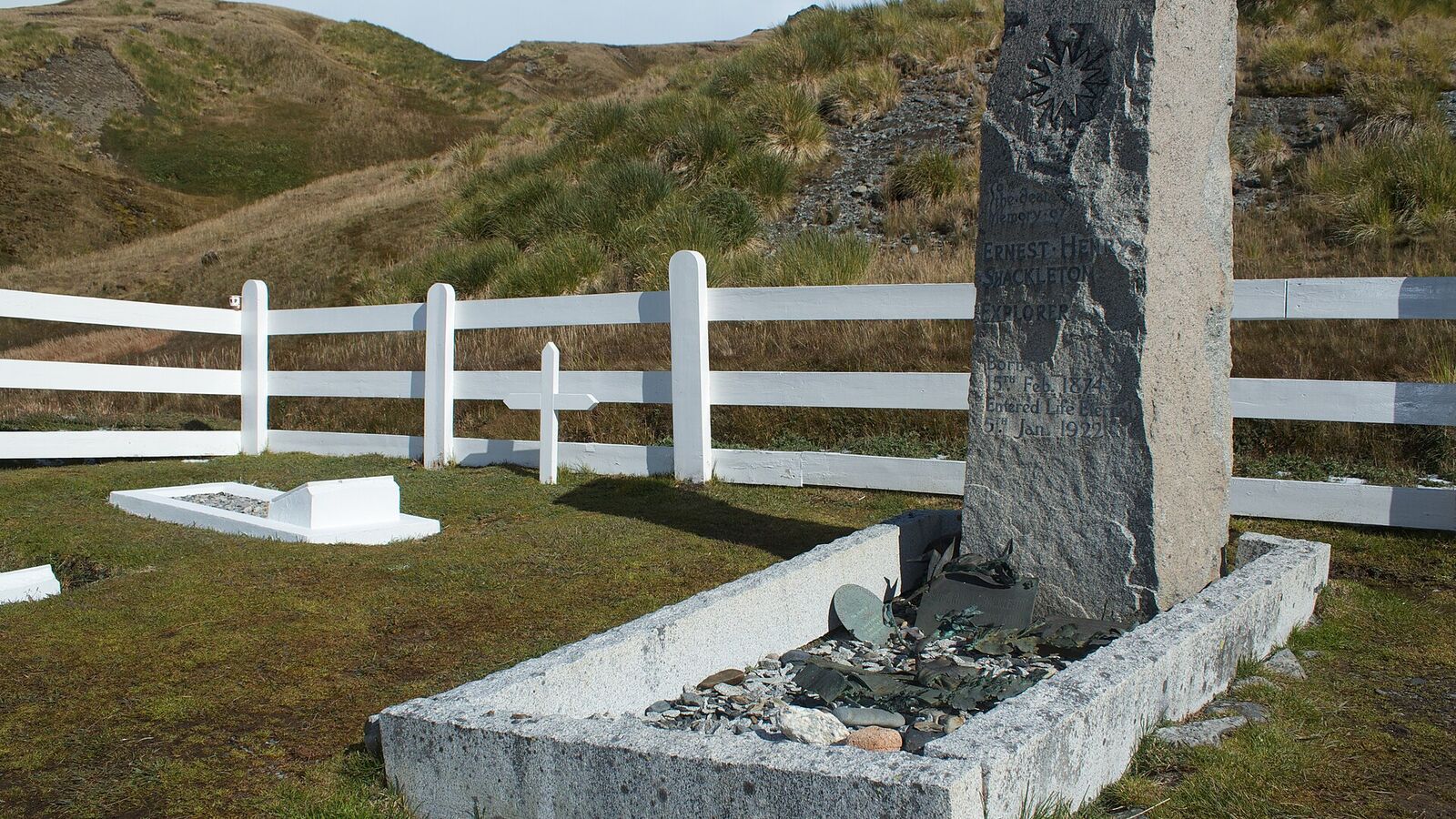 Het graf van Ernest Shackleton met granieten grafsteen achter een wit hek op de walvisvaardersbegraafplaats van Grytviken