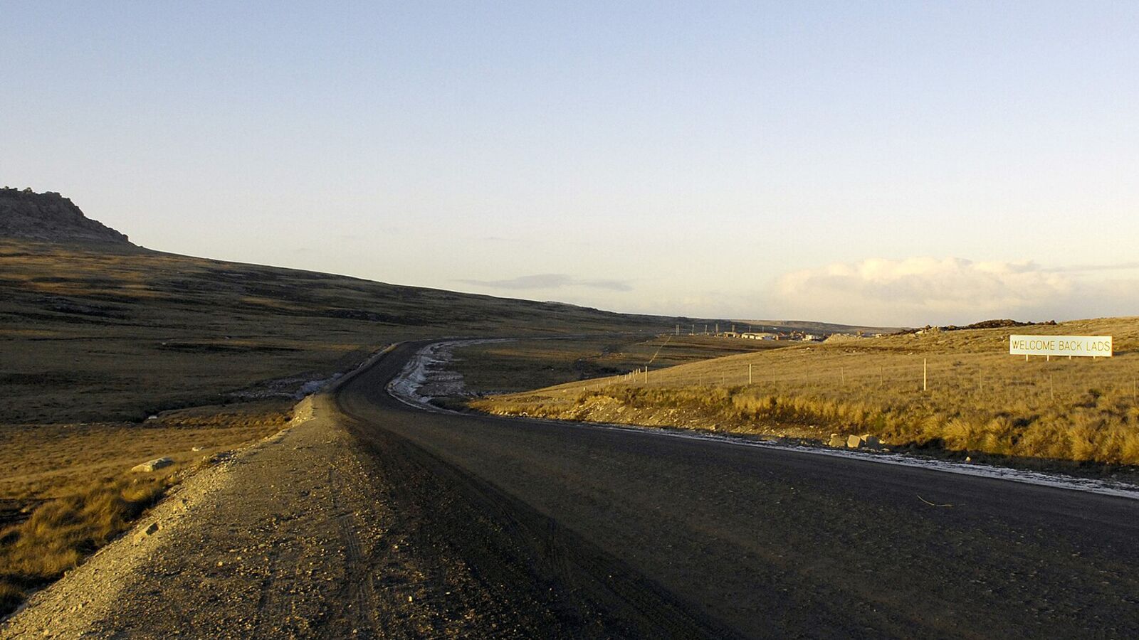 Grindweg door een leeg, golvend landschap tussen Goose Green en Stanley