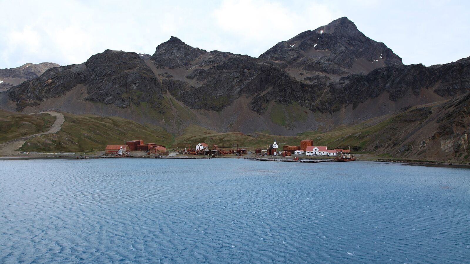 Het oude walvisvaartstation Grytviken aan een baai op Zuid-Georgië, met rode gebouwen en kale bergen